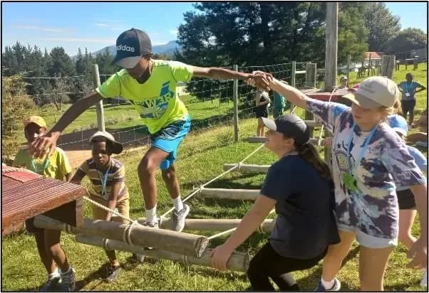 Children and adults working together on an outdoor balancing activity at Hobbiton